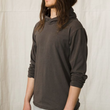 Load image into Gallery viewer, A handsome young man with long hair wears a charcoal grey hooded long sleeve pullover top with the sleeves pushd up